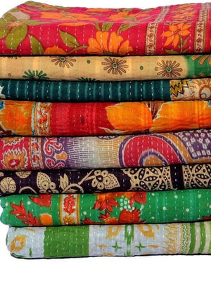 Stack of colorful patterned kantha quilts on a white background