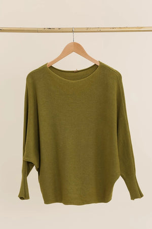 Green sweater on a wooden hanger against a beige background